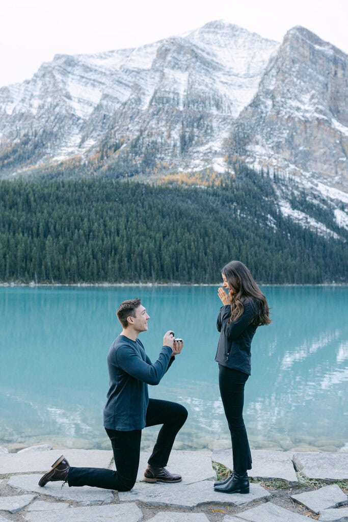 Romantic Lake Louise proposal in early October with turquoise water, fall foliage, and snow-dusted mountain peaks