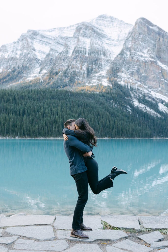 Surprise Lake Louise proposal with turquoise water, autumn trees, and snow on the mountain ridges