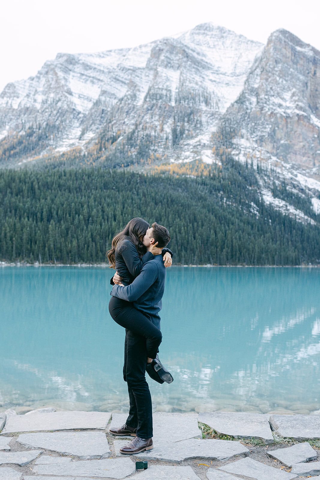 Couple celebrating a Lake Louise proposal surrounded by golden larches and snow-dusted peaks