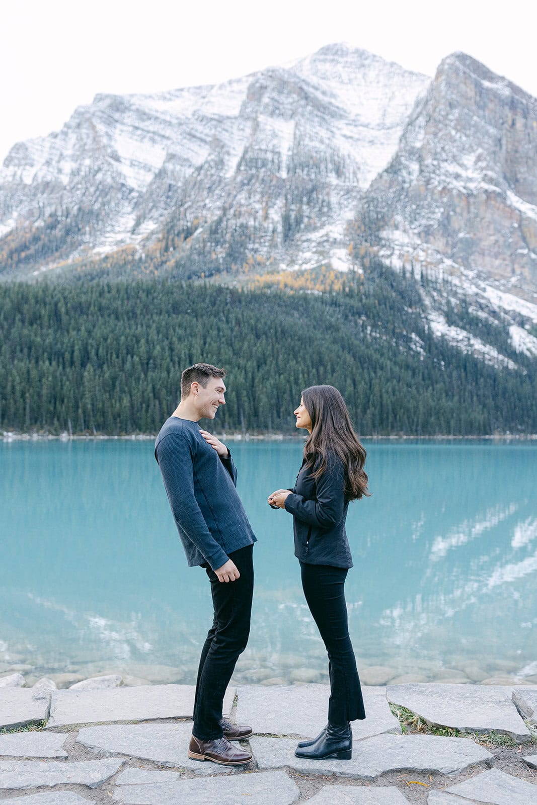Romantic engagement moment at Lake Louise with autumn tones and fresh snow on surrounding mountains