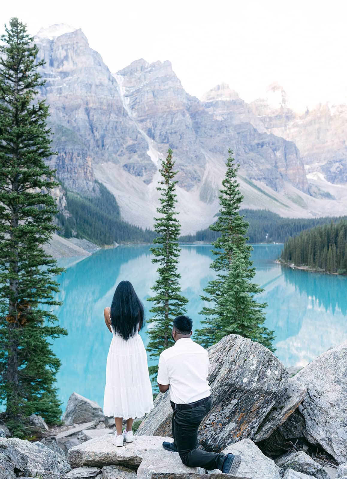Romantic engagement moment at Moraine Lake in Banff with rugged peaks and turquoise waters