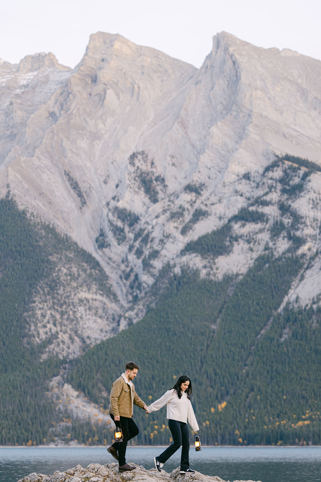 Surprise proposal moment at Lake Minnewanka shoreline with natural Rocky Mountain scenery