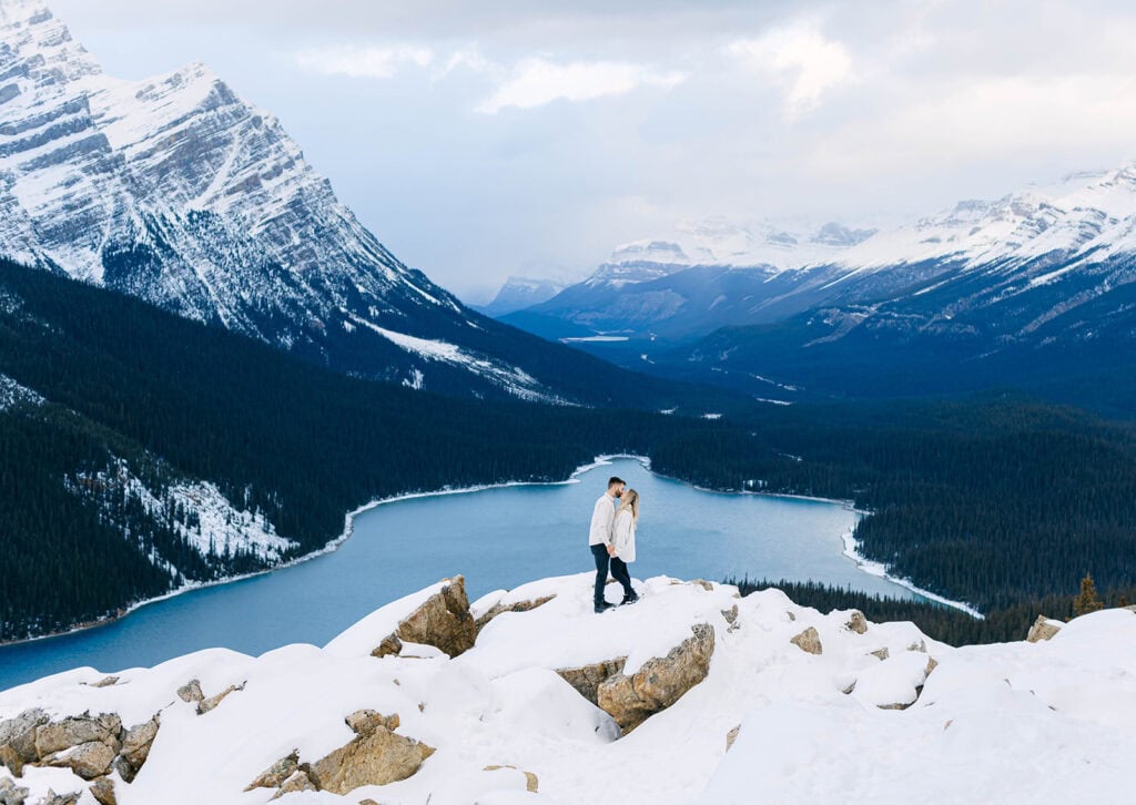 Winter Peyto Lake engagement photos with bright blue glacier-fed water and snow-covered Rocky Mountains in Banff National Park.