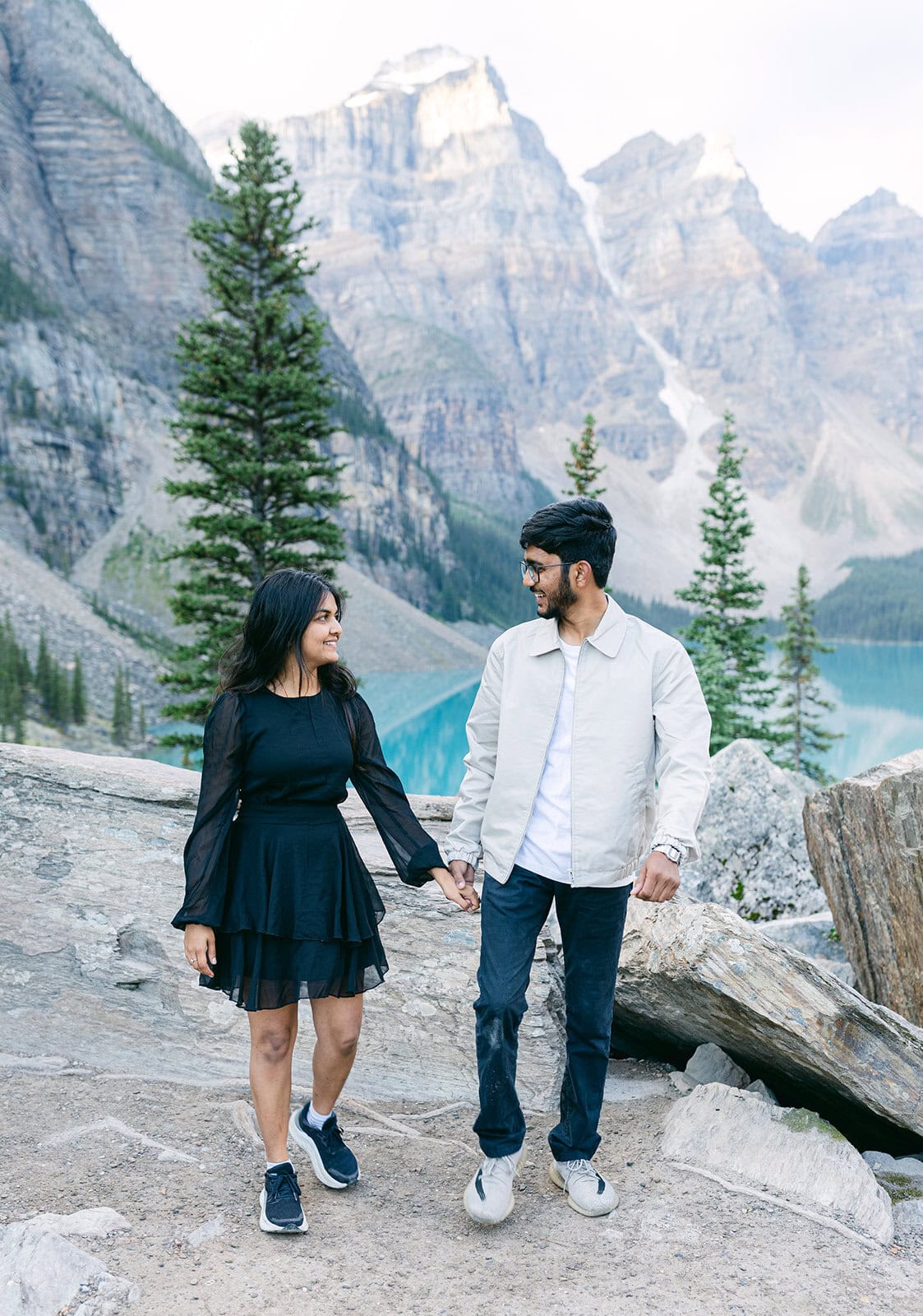 Couple walking by alpine lake during pre-wedding shoot in Banff National Park