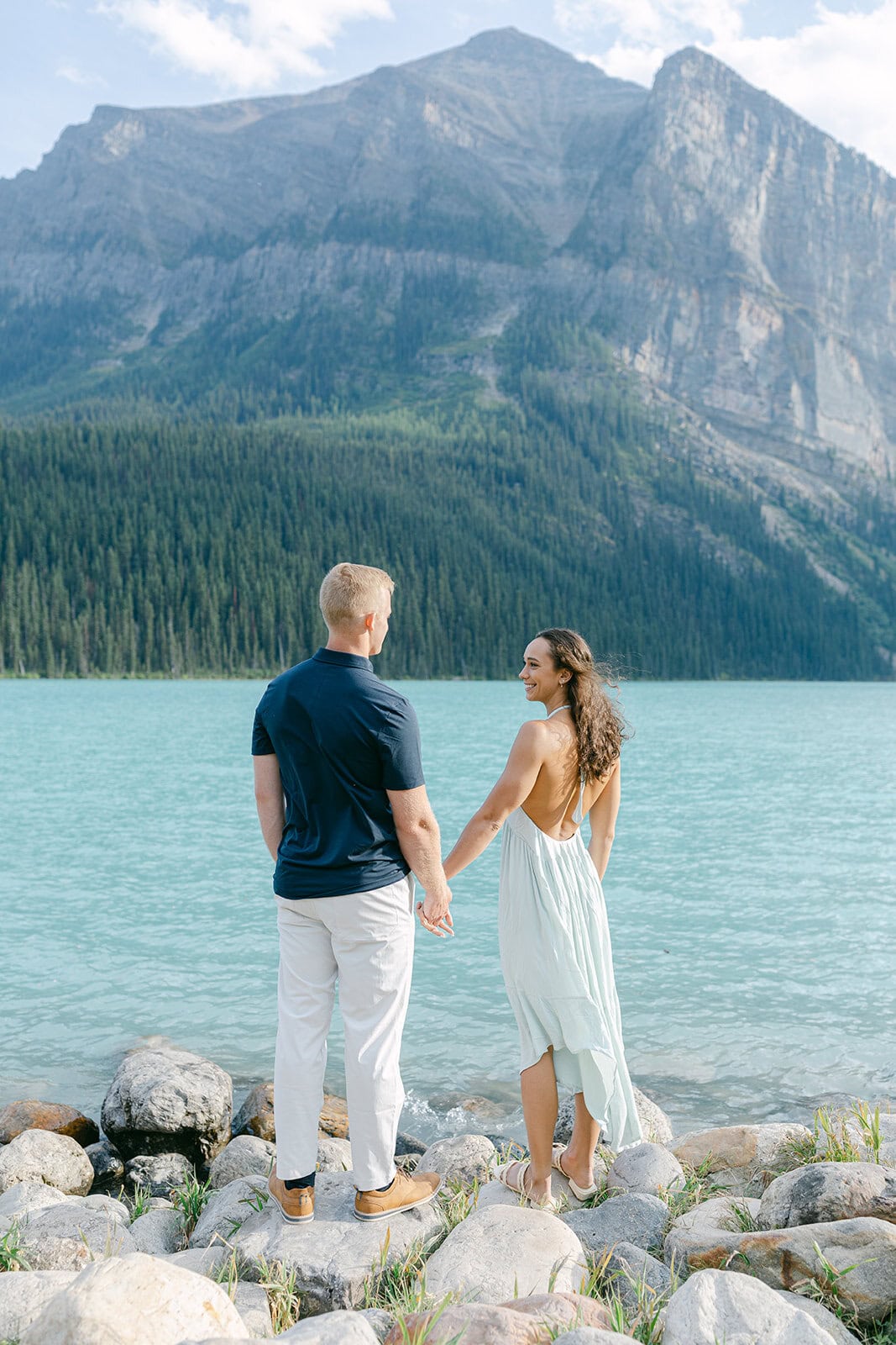 Couple holding hands near the lake during Lake Louise engagement photos