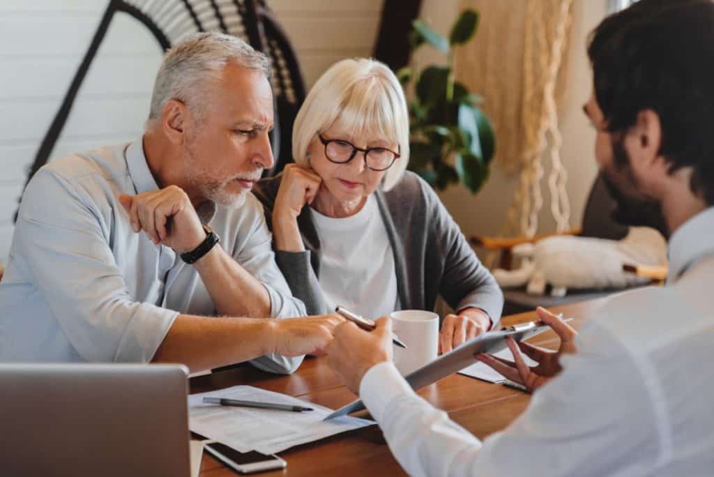 Concerned senior couple reviews paperwork with an attorney, discussing a low insurance settlement offer.