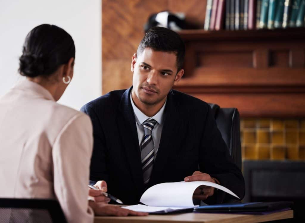 Property insurance claim lawyer consulting with a client in an office, reviewing documents related to a property insurance dispute.