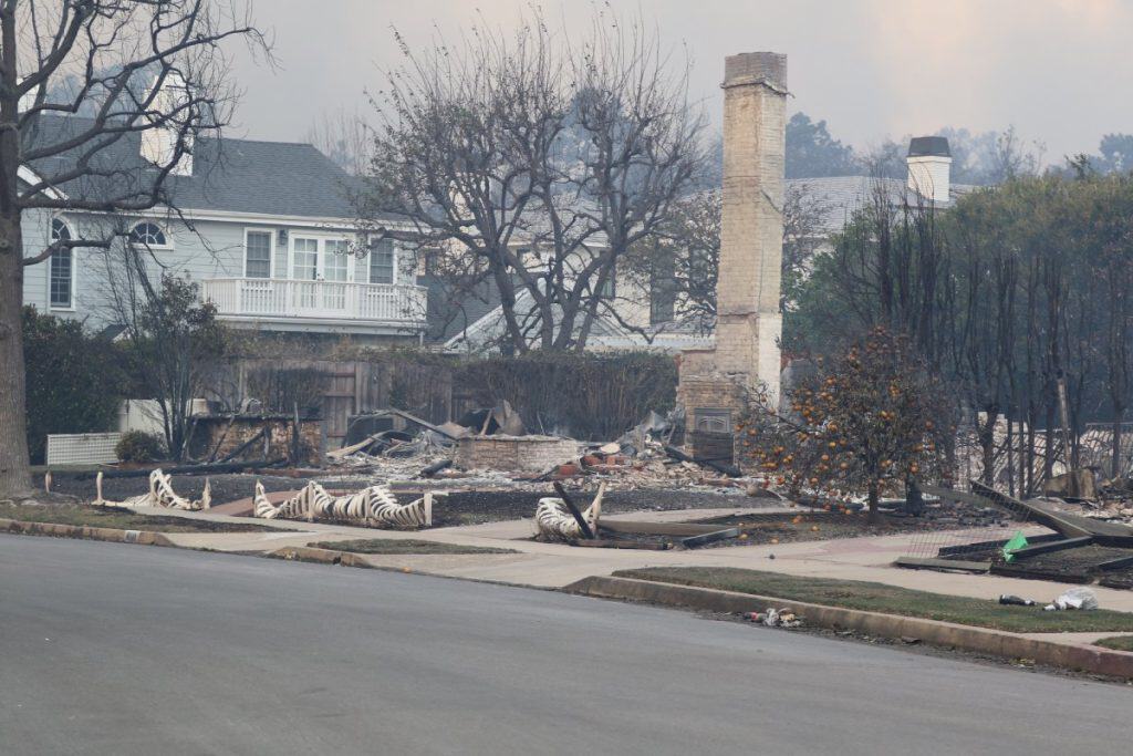 Burned-down residential property reduced to rubble with only a chimney remaining, representing a home considered a total loss requiring a full insurance estimate.