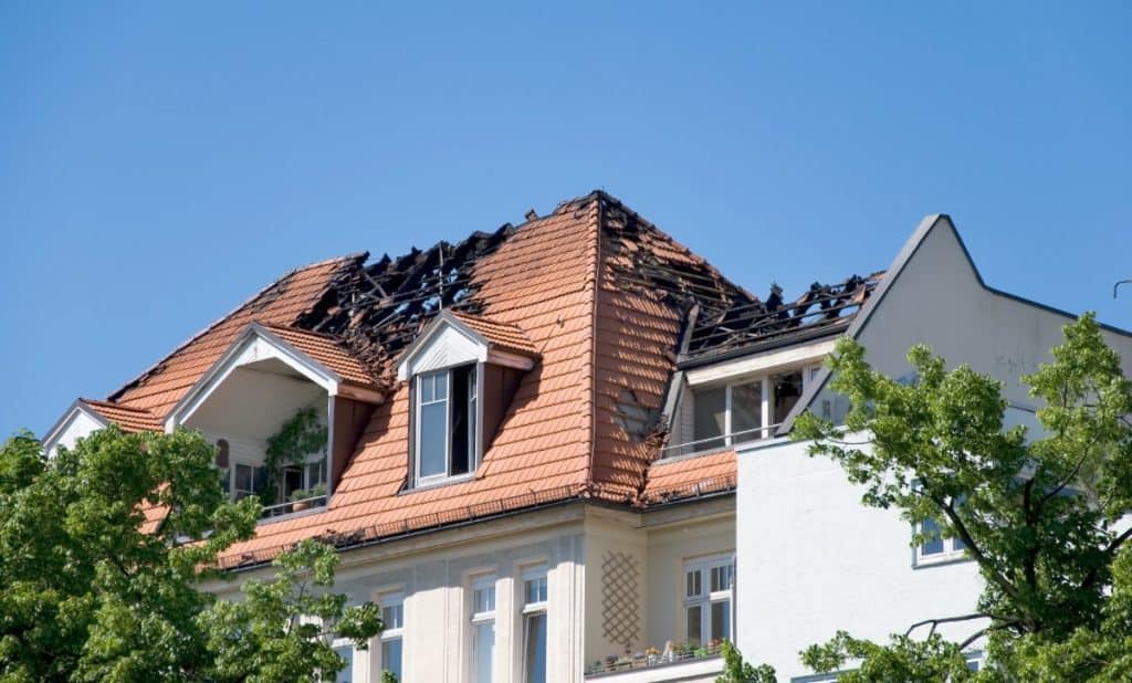 Burned roof of a residential building after a fire, illustrating the type of property damage where a house fire lawyer can help homeowners recover insurance claims and compensation.