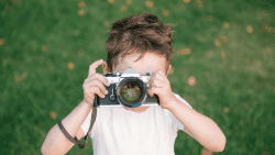 Boy using a vintage camera for documenting Montessori Family Summer Memories