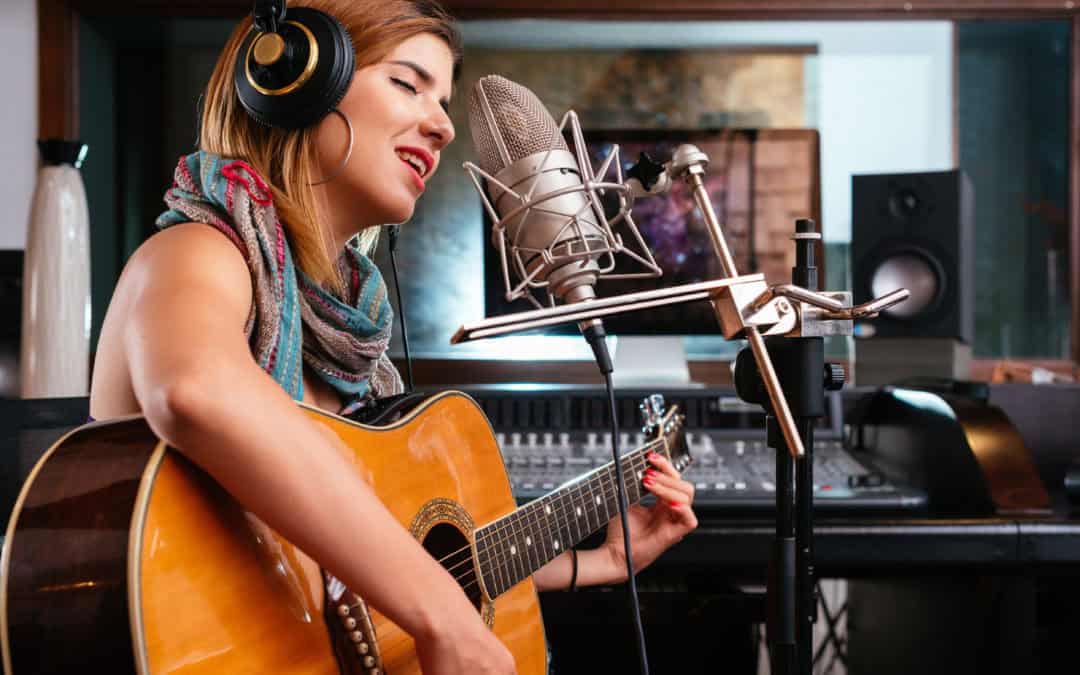 Young Woman With Guitar Recording A Song In The Studio