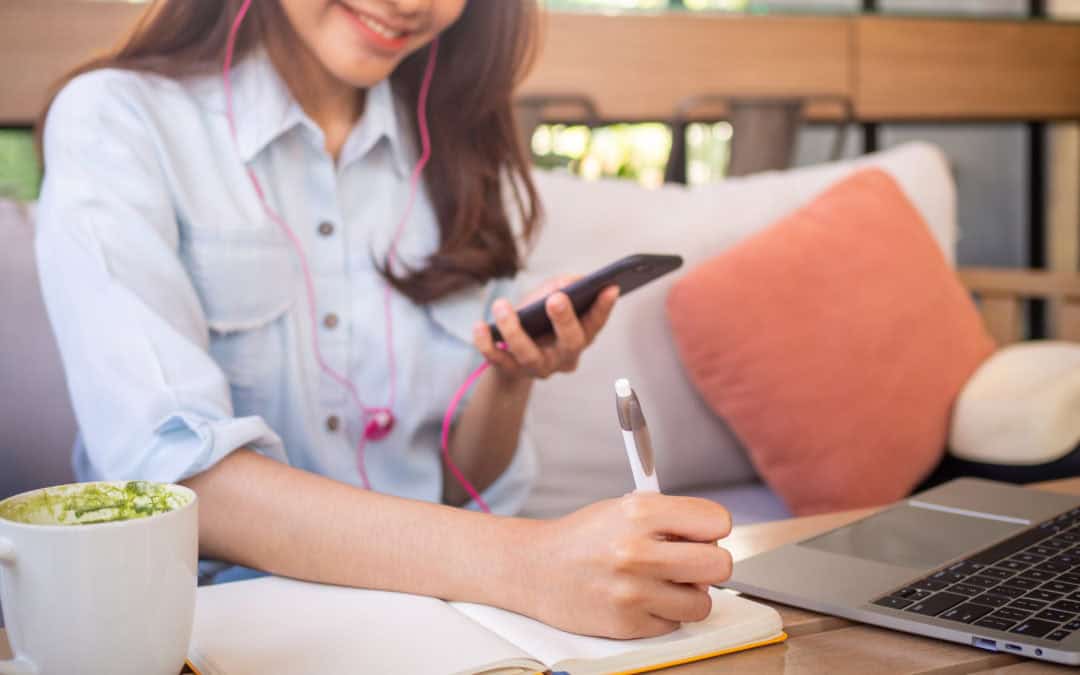 An Asian Woman Sitting Holding A Phone Listening To Music