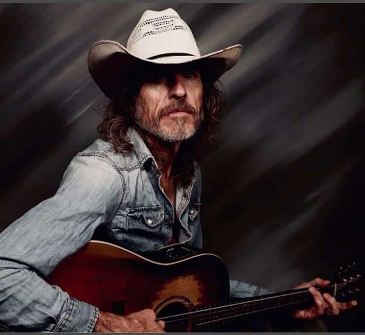 Guitarist wearing a cowboy hat, playing acoustic guitar, ideal for country or folk music performance.