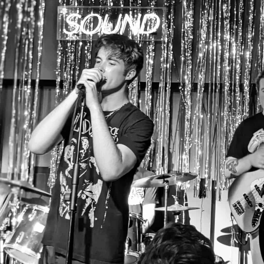 Vocalist singing passionately during a live performance at a music venue.