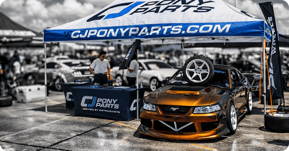 Car at Mustang Week under a GJPonyParts tent.