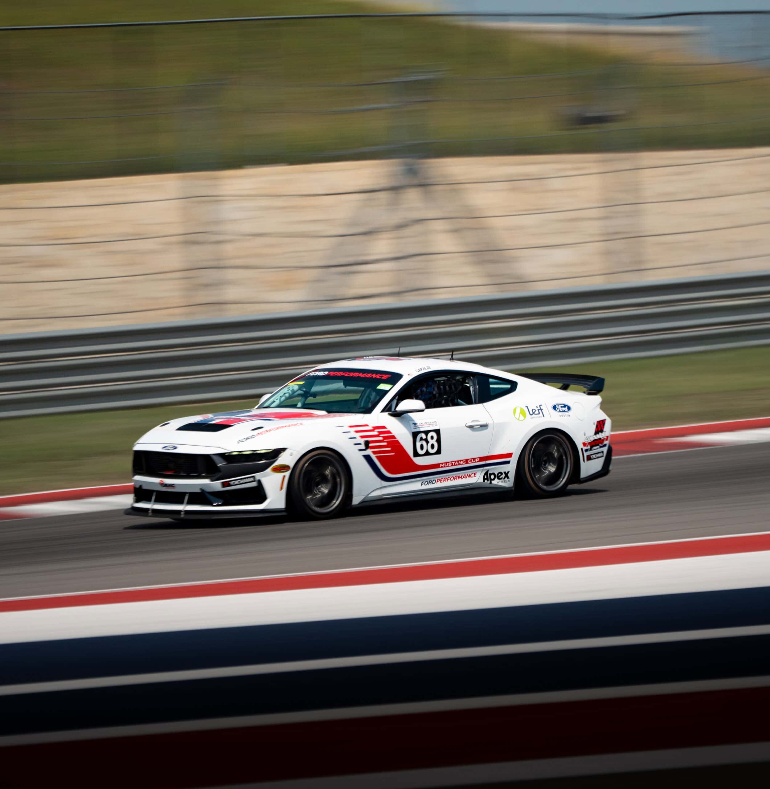 White race car with red and black accents on track during Mustang Week.