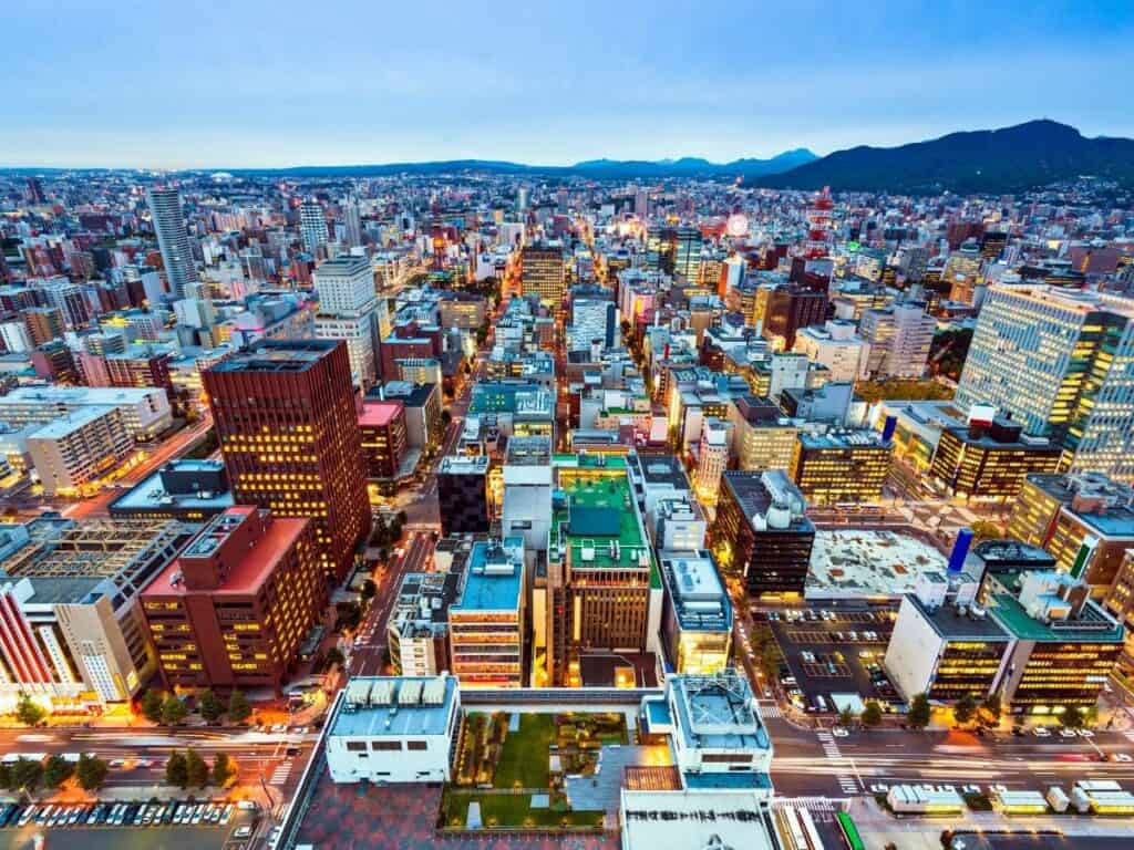 A panoramic view of Sapporo at dusk, with city lights starting to glow beneath a pastel sky—an urban highlight on any 2 week Hokkaido itinerary.