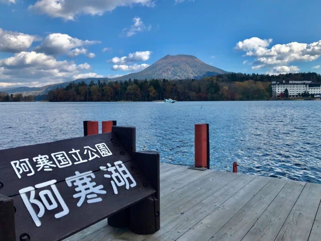 Tranquil view of Lake Akan with its wooden dock and a Japanese sign reading “Akan National Park”—a serene moment on a 2 week Hokkaido itinerary.