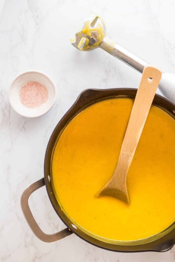 Immersion blender in a pot of vegan butternut squash soup, blended smooth and creamy.