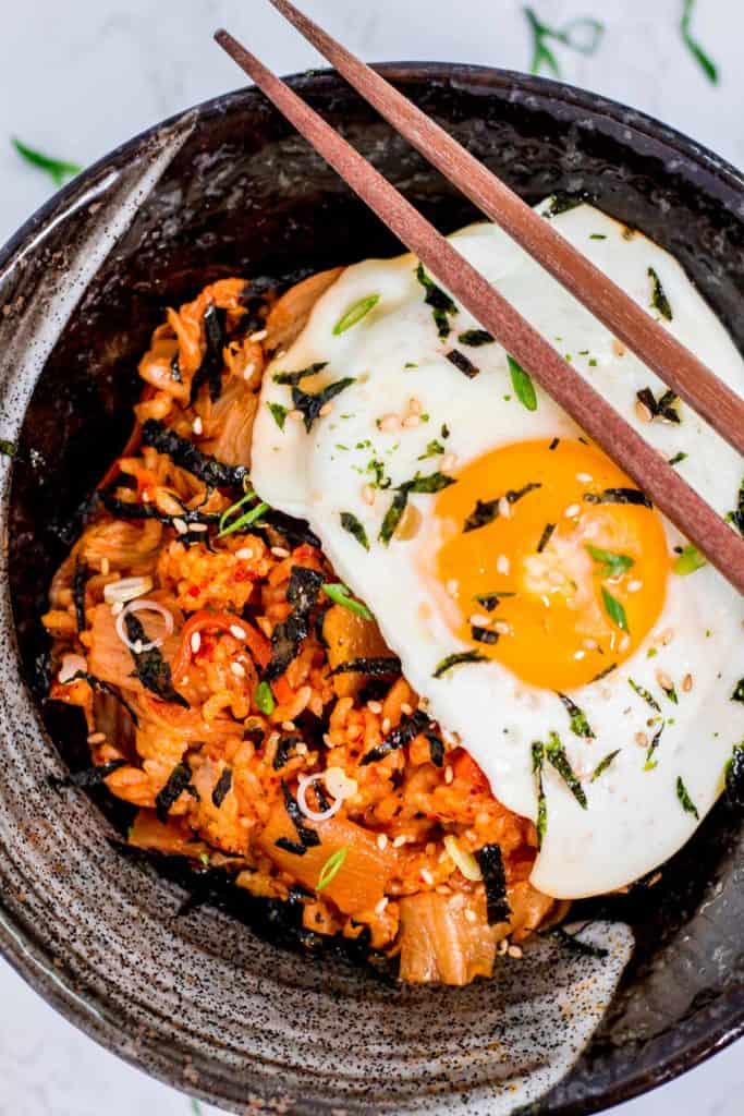 A black bowl full of kimchi fried rice with fried egg on top