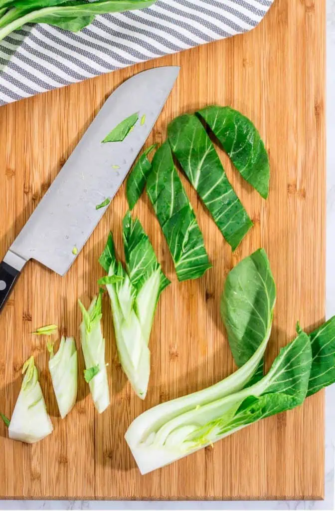 Chopped bok choy stems and leaves cut into bite-sized pieces on a cutting board.
