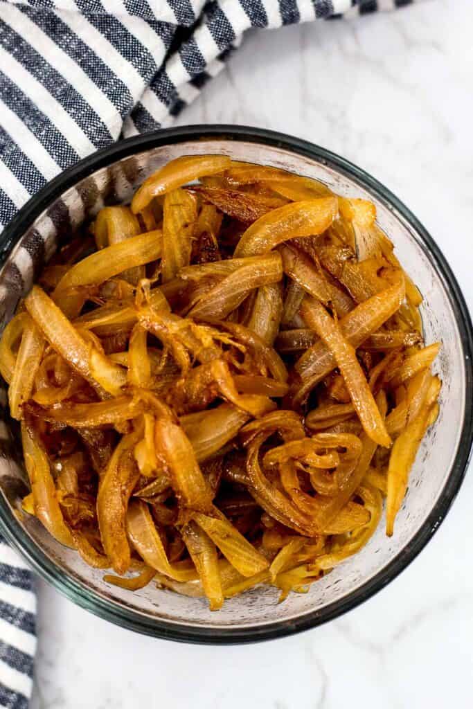 Quick caramelized onions cooked until golden brown and glossy, shown in a glass bowl