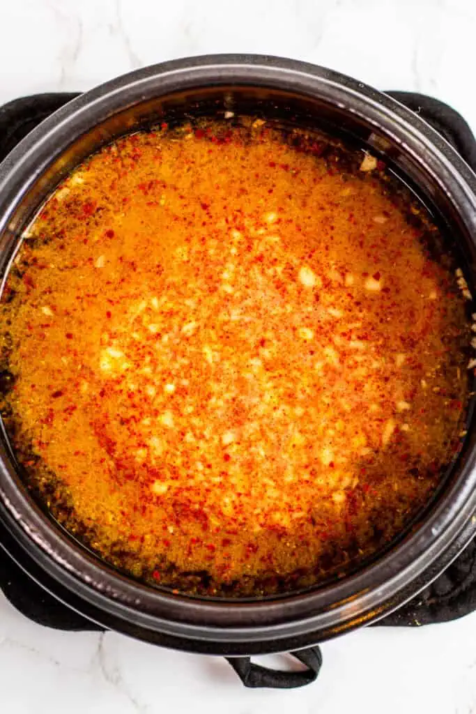 doenjang dissolved in water with garlic and gochugaru in a black clay pot.