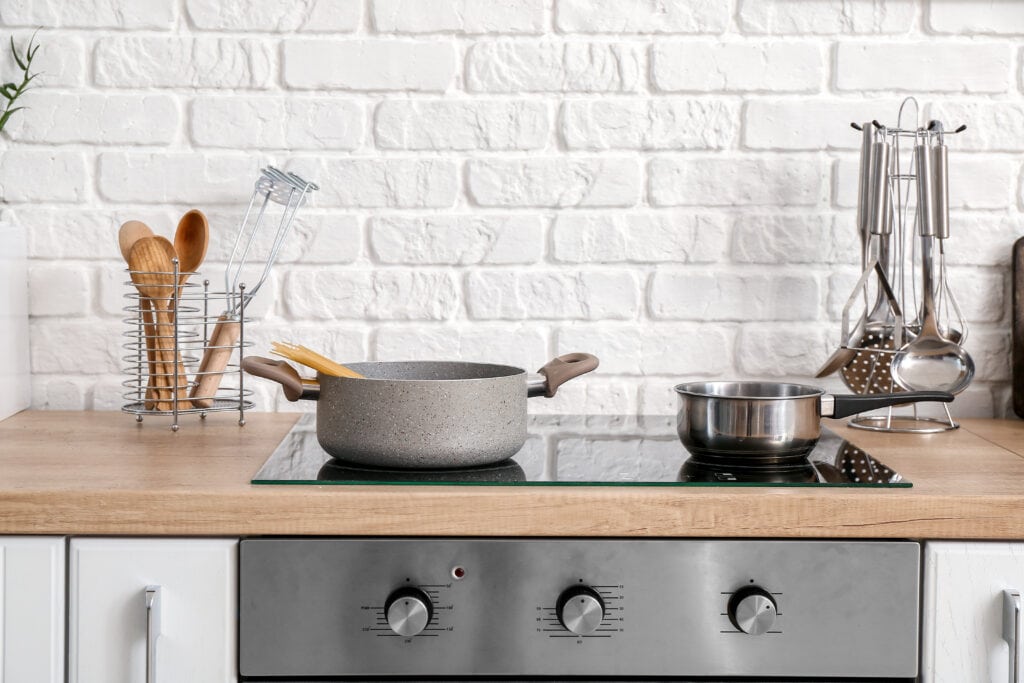 Pots on the stovetop in the kitchen with some utensils in the background.
