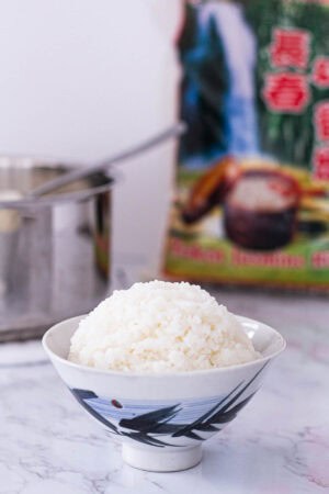 Cooked broken jasmine rice served in a small bowl with packaging in the background