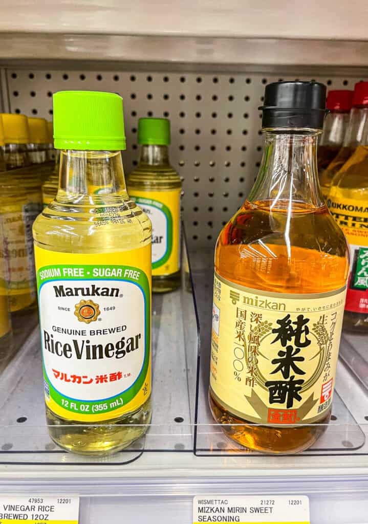 Close-up of Marukan genuine brewed rice vinegar bottle on a grocery store shelf, a staple ingredient in Japanese cooking and sushi rice.