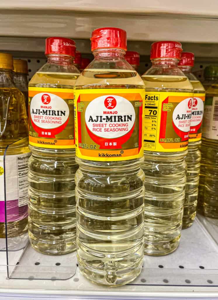 Close-up of Kikkoman Manjo Aji-Mirin bottles on a grocery store shelf, a sweet cooking rice seasoning used in Japanese cuisine.