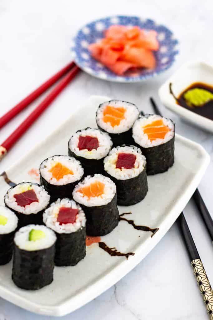 Plated maki rolls with tuna, salmon, and cucumber served with soy sauce, wasabi, and pickled ginger
