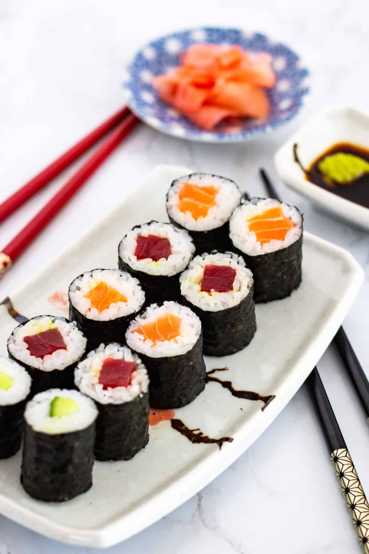 Plated maki rolls with tuna, salmon, and cucumber served with soy sauce, wasabi, and pickled ginger