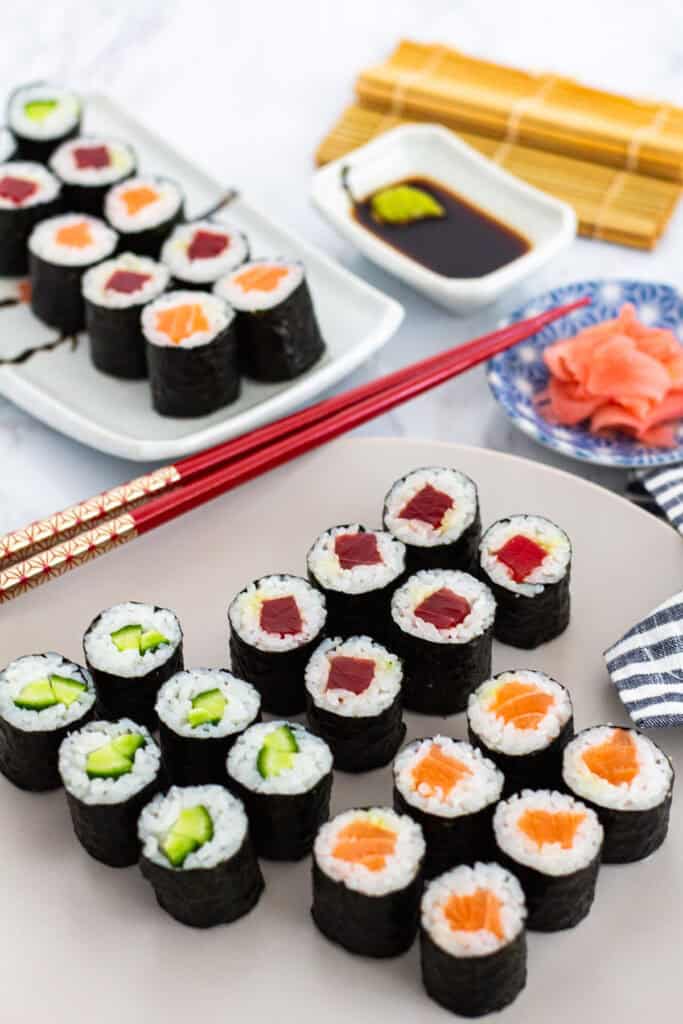 Assorted maki rolls with tuna, salmon, and cucumber on serving plates with soy sauce, wasabi, and pickled ginger