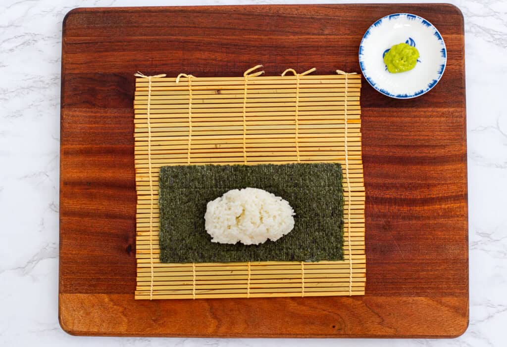 Sushi rice placed on nori sheet on bamboo mat for rolling hosomaki