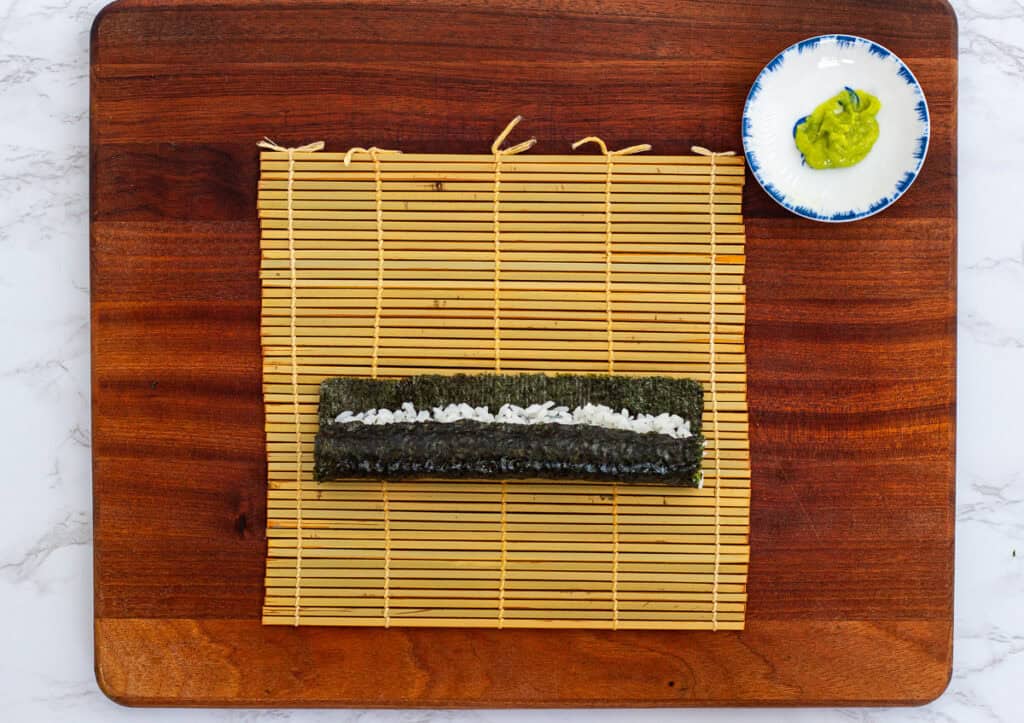 Partially rolled sushi showing a strip of rice on top, ready to be sealed and shaped into hosomaki