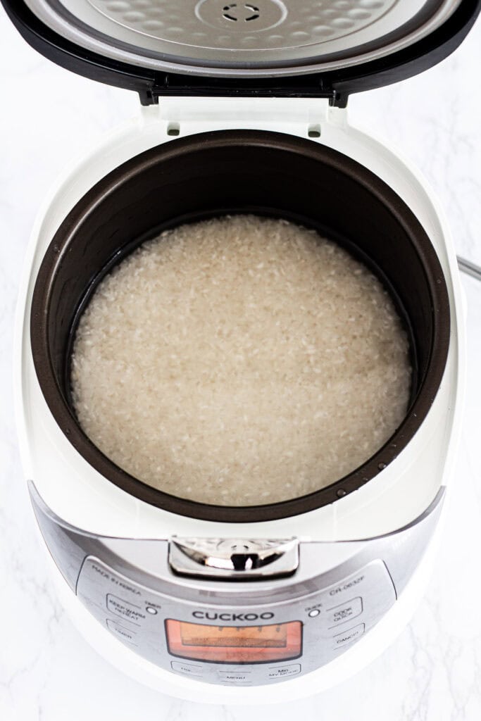 Rinsed short-grain sushi rice in a Cuckoo rice cooker, ready to cook