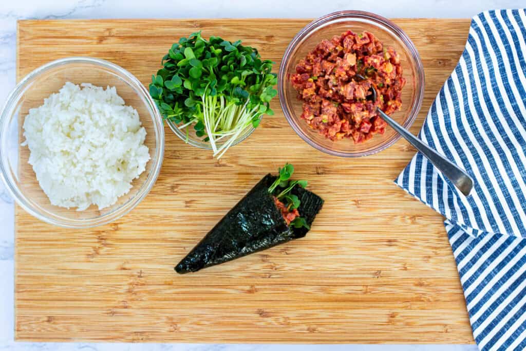Finished spicy tuna temaki cone rolled with sushi rice, spicy tuna, and radish sprouts in crisp nori, ready to serve