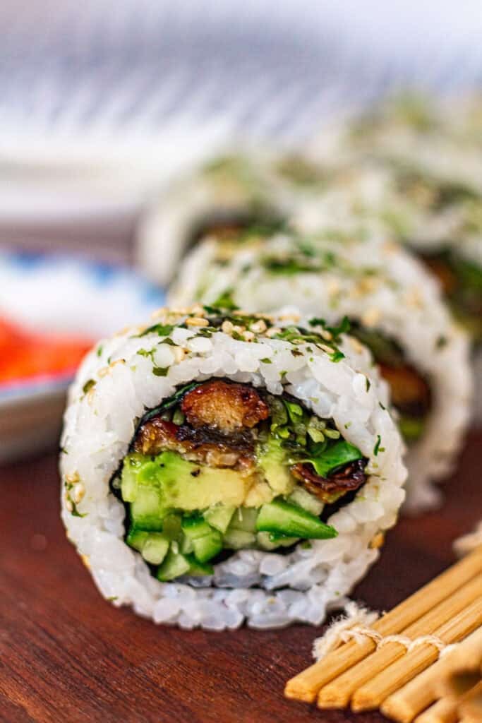 Macro shot of sliced unagi uramaki roll highlighting the grilled eel, avocado, cucumber, and sprouts inside rice and nori