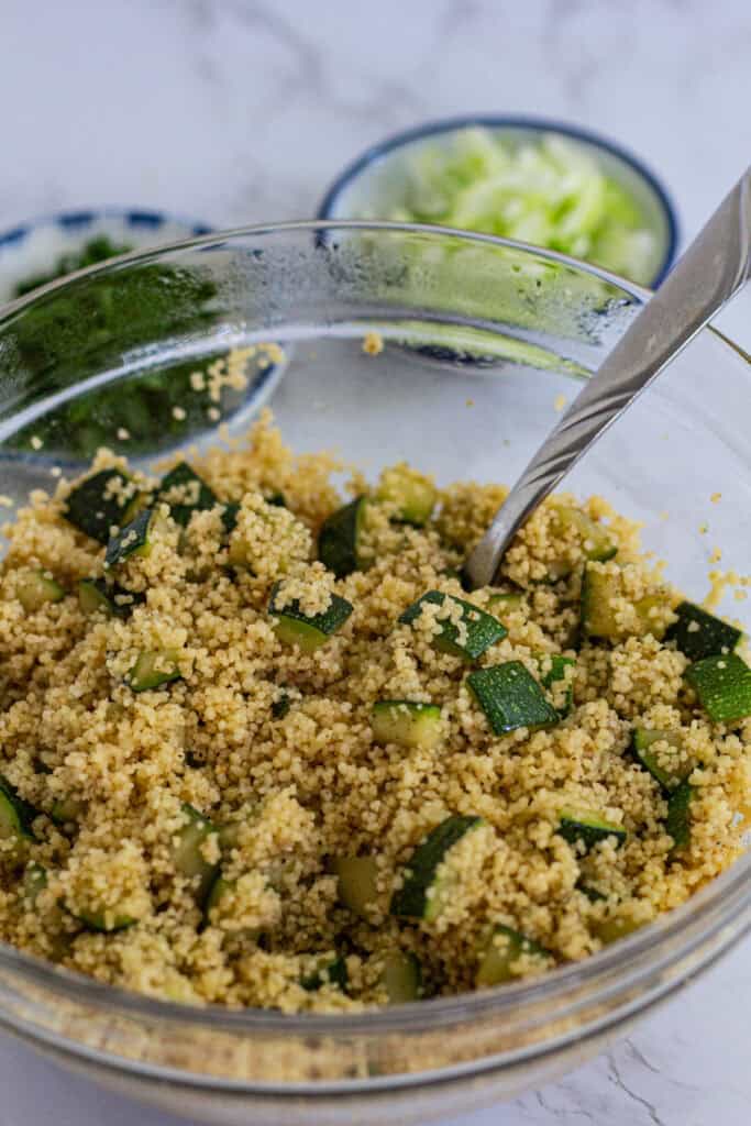Bowl of fluffed couscous mixed with sautéed zucchini and garam masala before adding herbs