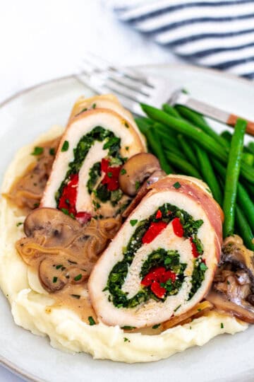 Chicken roulade slices served over mashed potatoes with marsala sauce and green beans on the side.