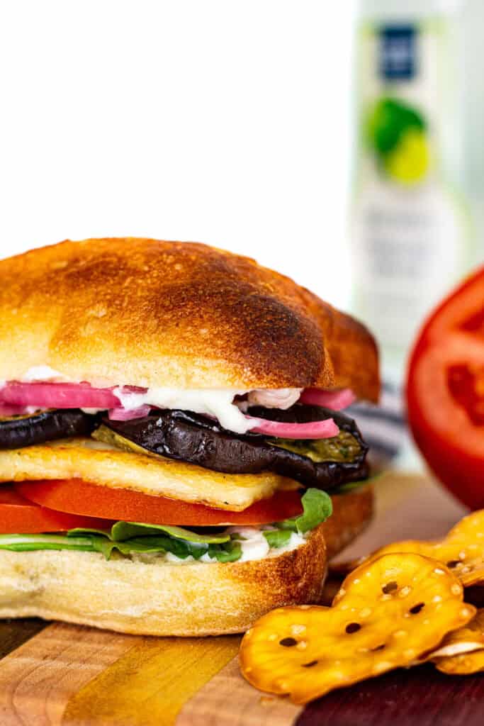 Mediterranean roasted eggplant and halloumi sandwich stacked with arugula, tomato, and pickled onion on toasted ciabatta