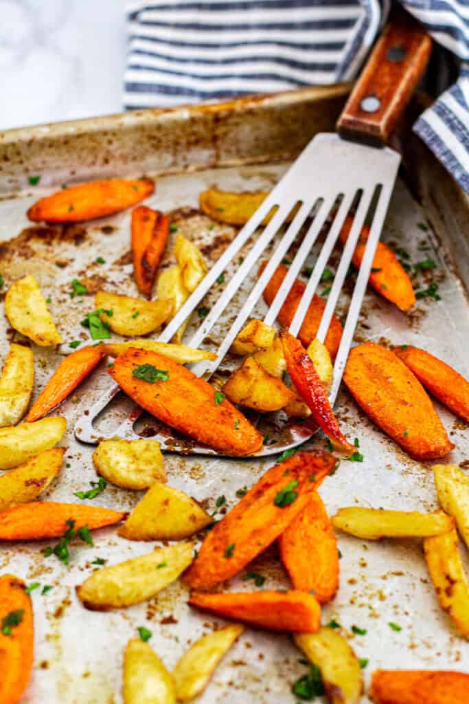 Moroccan roasted carrots and parsnips on a baking sheet, garnished with fresh parsley
