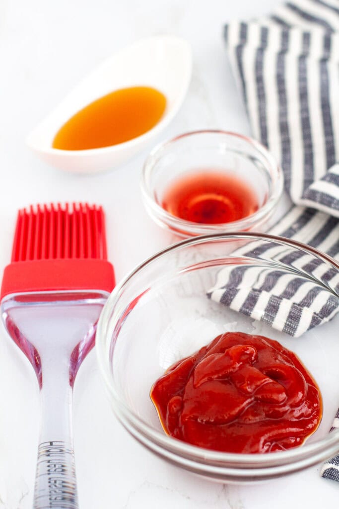 Ketchup, honey, and red wine vinegar in small bowls with a red pastry brush for meatloaf glaze