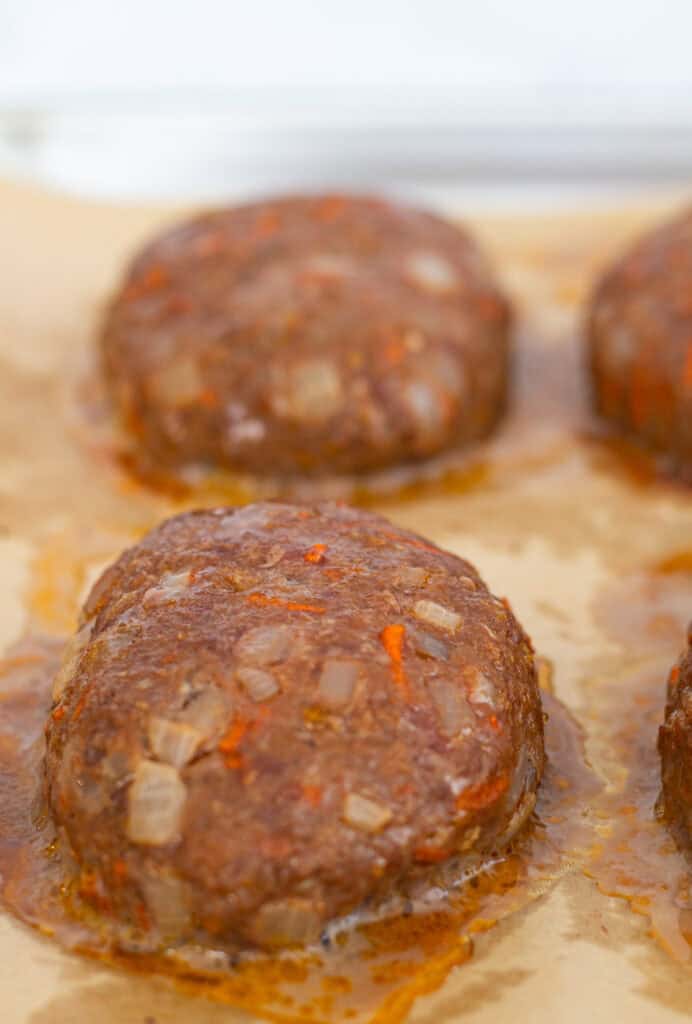 Juicy mini meatloaf patties baked on a parchment-lined tray before glazing
