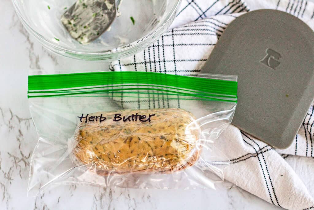 Homemade herb butter log wrapped in parchment paper, ready to be chilled or frozen for later use.
