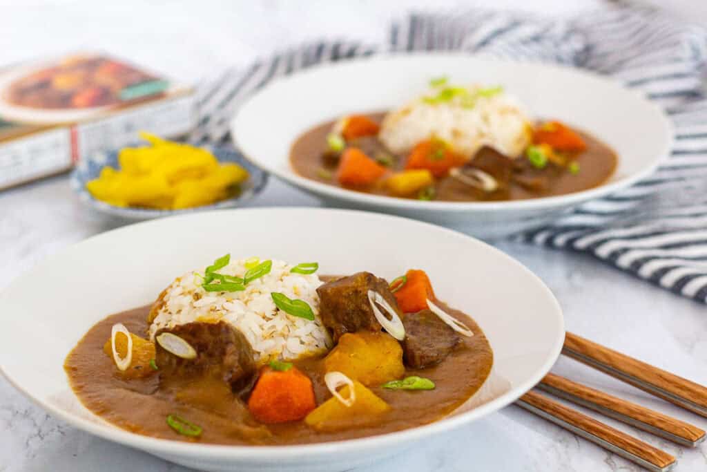 Japanese beef curry served with steamed rice, topped with green onion slices.