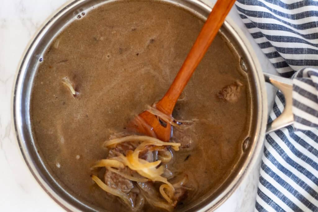 Beef and caramelized onions simmering in water with apple sauce for Japanese beef curry.