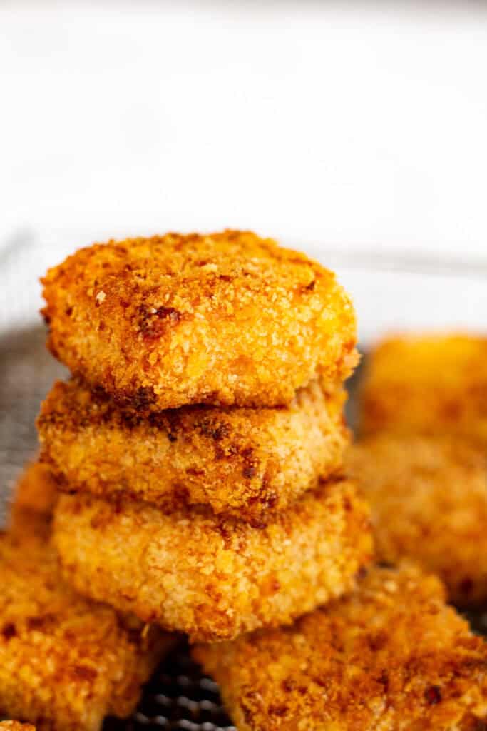 Close-up stack of golden mac and cheese bites showing crunchy panko parmesan coating.
