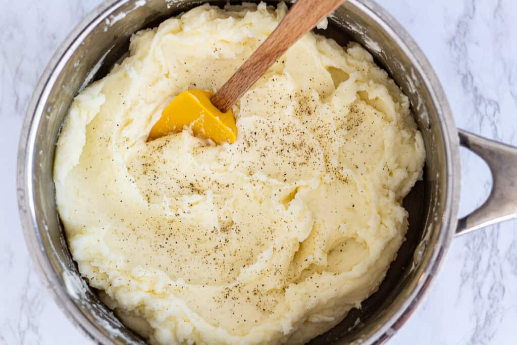 Fluffy mashed potatoes in a saucepan with black pepper on top